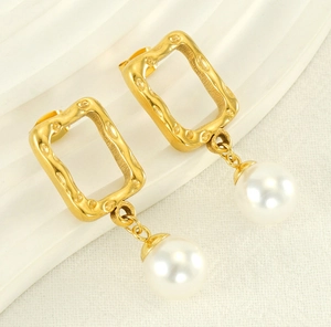 Close-up of square gold textured metal earrings with elegant white pearls detail