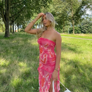 Détail d'une robe bustier rose à imprimé fleuri avec fente latérale et ourlet volanté