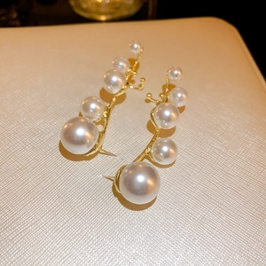 Macro view of gradient white pearls on gold curved earring studs with a polished finish