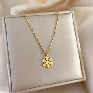 Close-up of gold snowflake pendant necklace on a beige silk box for women