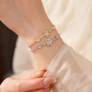 Dettaglio di bracciali a fiori in oro e argento con zirconi scintillanti su sfondo di seta