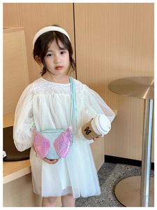 Detail of cute kid's shoulder bag featuring shiny pink wings on light blue textured fabric