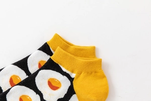 Close-up of black low cut socks with fried egg patterns and bright yellow cuffs