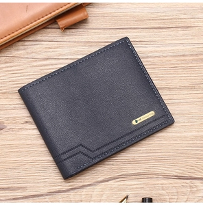 Detail of navy blue textured leather wallet with metal logo on wooden desk