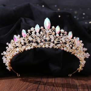 Close-up of golden bridal crown with sparkling AB crystals on dark velvet fabric