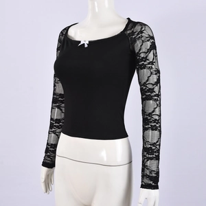 Detalle de top ajustado negro con puños de encaje y lazo blanco en el cuello