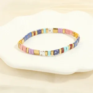 Close-up of colorful Tila beads and gold accents on a bohemian woven stretch bracelet