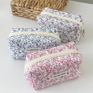 Close-up of quilted floral makeup bags in lilac, blue and pink with cotton texture
