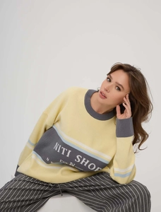 Detail of the oversized knit sweater showing NITI SHOP print and grey striped accents