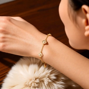 Détail d'un bracelet fleuri plaqué or 18K avec nacre sur un poignet de femme