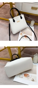 Detail view of white and black faux leather handbag with gold-tone hardware and buckle