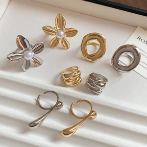 Macro view of gold and silver metallic floral rings with pearls on a ceramic tray