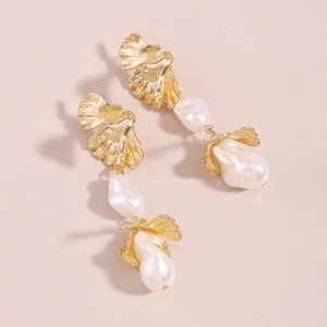 Macro detail of golden ginkgo leaf design with baroque irregular white pearls earrings