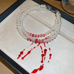 Detail of three-layer pearl necklace with red crystal beads and teardrop pendant on display