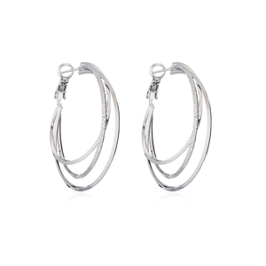 Macro detail of multi-layered silver metal hoop earrings with sparkling frosted finish