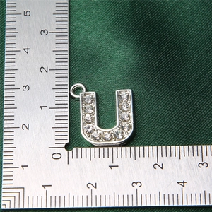 Macro view of silver U-shaped alloy charm with rhinestones next to a measuring ruler