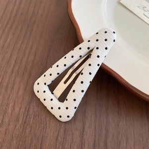 Macro di fermaglio per capelli triangolare a pois neri su tavolo in legno scuro