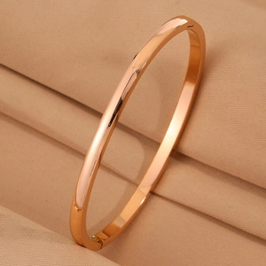 Detail of rose gold curved bangle with a polished mirror finish on silk fabric