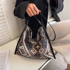 Close-up of bohemian geometric pattern canvas tote bag with woven texture and black handles