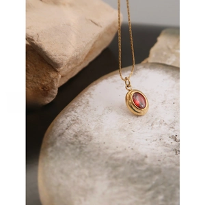 Macro shot of oval red gemstone pendant on a gold plated stainless steel necklace