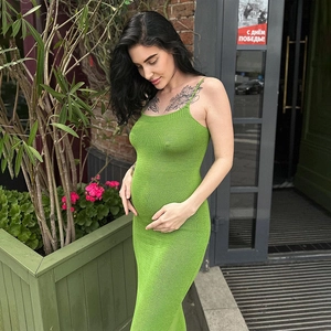 Détail de la robe de maternité longue en tricot vert montrant le tissu extensible et fendu