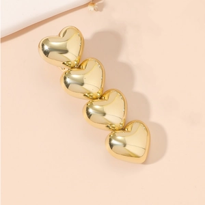 Detail of four golden alloy hearts on a sleek hair clip with mirror finish shine