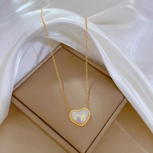 Dettaglio di un ciondolo a perla a forma di cuore con bordo dorato su catena in titanio