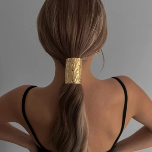 Minimalist gold hammered metal ponytail holder for women shown on a model's low ponytail