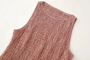 Détail de robe sans manches à carreaux rouge et blanc avec texture plissée au col