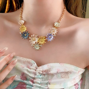 Close-up of model wearing colorful enamel daisy pendants on a gold plated chain necklace