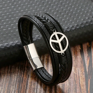 Detail of multi-layer braided leather bracelet with silver peace pendant and magnetic clasp