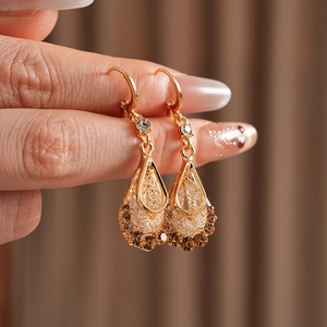 Macro detail of vintage gold teardrop earrings with brown and clear zircon stones