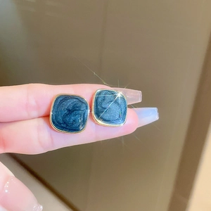 Macro detail of vintage blue marble resin earrings with elegant gold metal trim