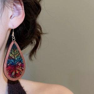 Close-up of teardrop wood earrings with colorful butterfly wing patterns on model