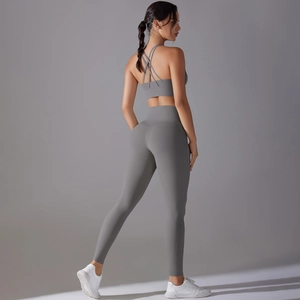 Detail of the cross-back sports bra and high-waisted gray yoga leggings on a model