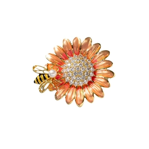 Detail of enamel sunflower brooch featuring a sparkling bee with a pearl accent