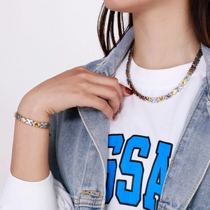 Close-up of dual-tone heart and X-shaped link necklace and bracelet set on a model