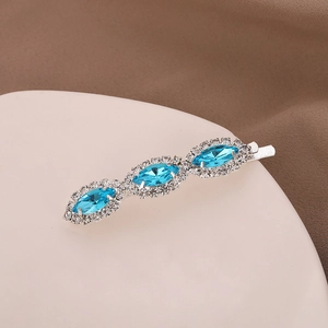 Elegant silver hair clip with blue oval gemstones and clear crystals on a white surface
