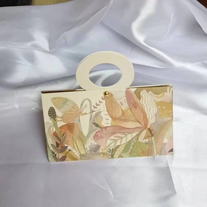 Detail of pink floral gift box with gold foil accents on a white satin background