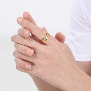 Elegant gold feather ring with white diamond inlay on model hand, minimalist style