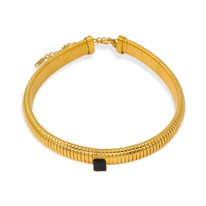Detail of a gold ribbed necklace featuring a central square black gemstone and lobster clasp