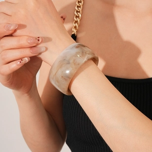 Detail of vintage-style wide marble pattern resin bangle in brown and white on wrist