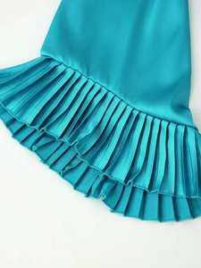 Detail of teal satin dress showing intricate pleated hemline texture and glossy fabric