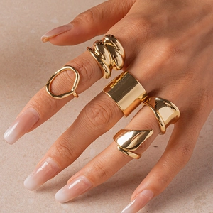 Close-up of five-piece gold geometric ring set with textured irregular design on hand