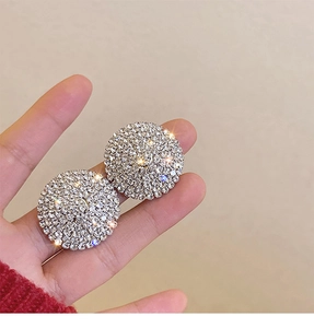 Close-up of sparkling full crystal pavé round stud earrings held in hand