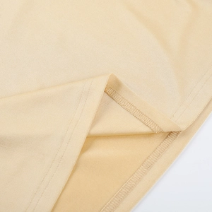 Gros plan détaillé sur la texture du tricot beige et les doubles coutures de précision sur l'ourlet