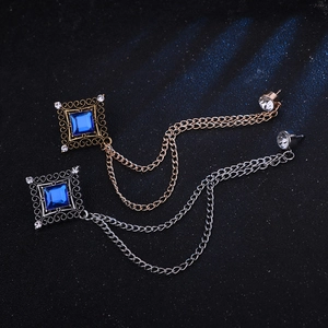 Detail of square vintage brooches with blue stones and tassels in gold and silver