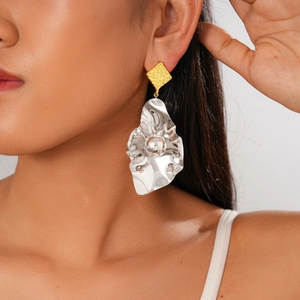 Detail of artistic mixed metal geometric square and petal earrings on a model