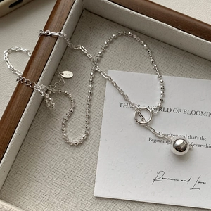 Macro detail of S925 sterling silver beaded necklace with rectangular link chain on a tray