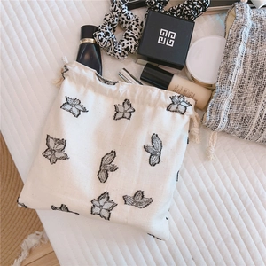 Detail of drawstring canvas bag with black embroidered butterflies on a quilted surface